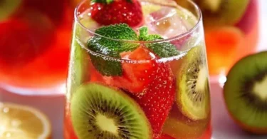 Glas Erdbeer-Kiwi-Limonade mit frischen Früchten im Hintergrund