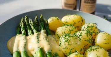Grüner Spargel mit Hollandaise und Kartoffeln auf einem Teller angerichtet