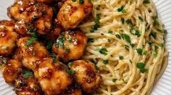 Honig-Knoblauch-Hähnchen serviert mit cremigen Spaghetti auf einem Teller