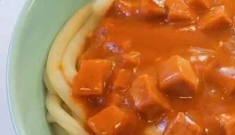 Makkaroni mit Tomatensoße und Jagdwurst auf einem Teller serviert.