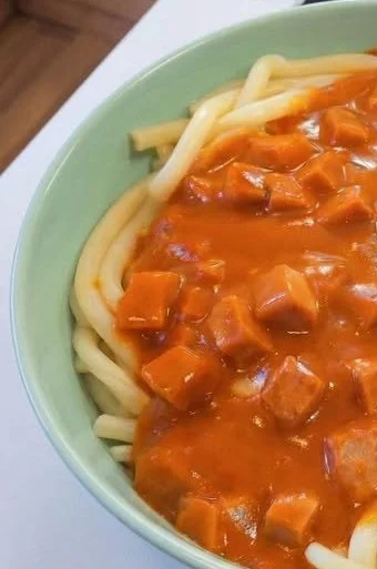 Makkaroni mit Tomatensoße und Jagdwurst auf einem Teller serviert.