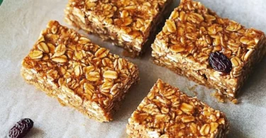 Gesunde Müsli-Riegel auf einem Holztisch mit Nüssen und Trockenfrüchten
