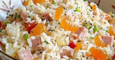 Reissalat mit Mandarinen und frischem Gemüse auf einem Teller.