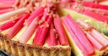Leckere Rhabarber-Vanille-Tarte auf einem rustikalen Holzbrett serviert.
