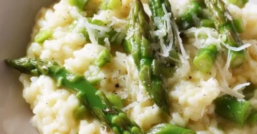 Leckeres Risotto mit grünem Spargel auf einem Teller serviert.