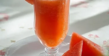 Erfrischendes Wassermelonengetränk in einem Glas mit Wassermelonenstücken.