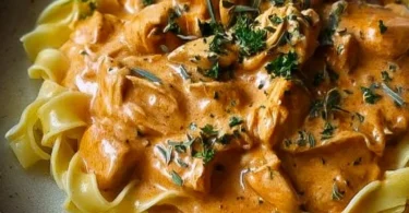 Cremiges Hähnchenragout mit Bandnudeln auf einem Teller garniert