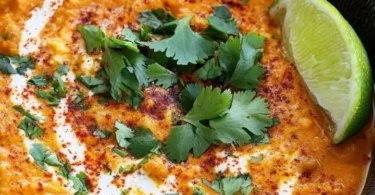 Eine Schüssel Linsen-Dal serviert mit frischen Kräutern und Gewürzen