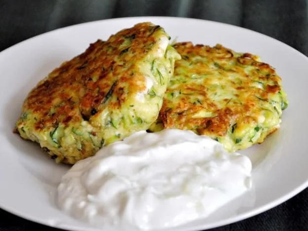 Leckere Zucchini-Feta-Puffer auf einem Teller serviert.