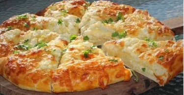 Leckeres Griechisches Käsebrot mit Feta und Kräutern auf einem Holzbrett.
