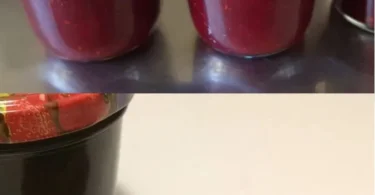 Glas mit selbstgemachter Johannisbeer-Marmelade auf einem Holzbrett