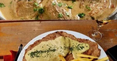 Schweineschnitzel mit Sahnesauce und Reis auf einem Teller serviert