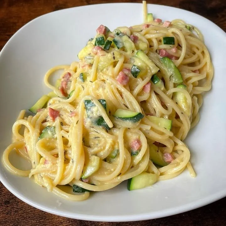 Zucchini Carbonara mit Nudeln und frischen Zutaten auf einem Teller