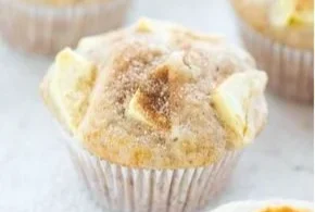 Frische Apfel-Muffins auf einem Holzbrett dekoriert mit Zimt.