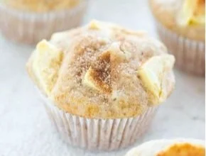Frische Apfel-Muffins auf einem Holzbrett dekoriert mit Zimt.