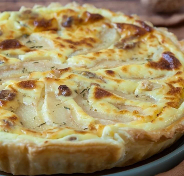 Leckere Birnen-Tarte mit Ziegenfrischkäse auf einem Tisch serviert