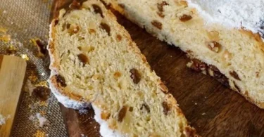 Butterstollen mit Trockenfrüchten und Puderzucker serviert auf einem Holzbrett