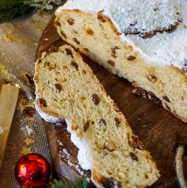 Butterstollen mit Trockenfrüchten und Puderzucker serviert auf einem Holzbrett