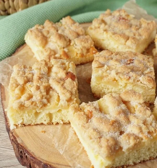 Einfacher Apfelkuchen vom Blech mit Streuseln auf einem rustikalen Tisch.