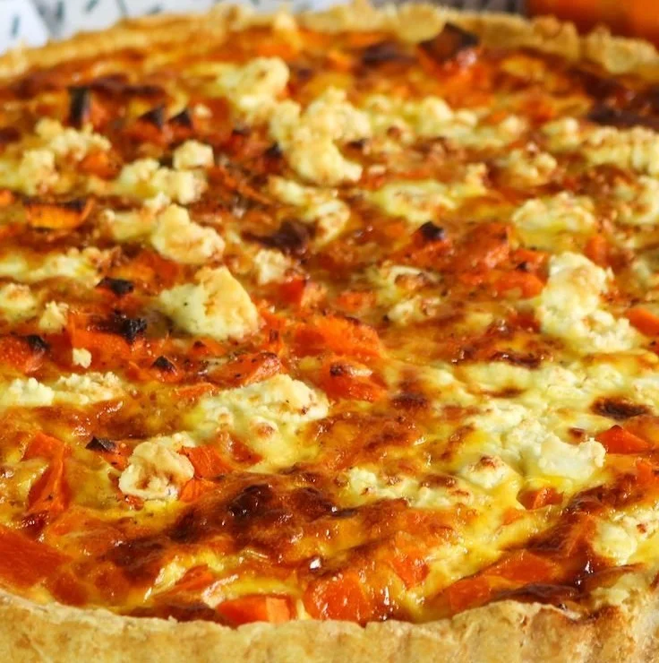 Kürbis-Quiche mit Feta auf einem Holzbrett serviert