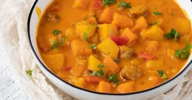 Kürbisgulasch mit Kartoffeln in einer bunten Schüssel serviert