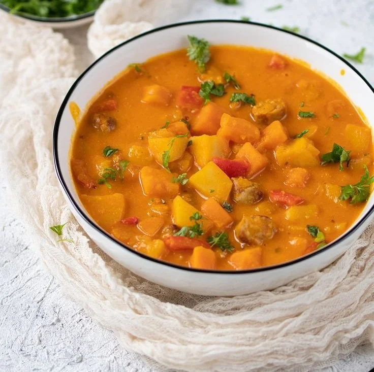 Kürbisgulasch mit Kartoffeln in einer bunten Schüssel serviert