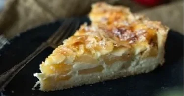 Saftige Apfeltarte mit Schmand und Mandeln auf einem Tablett präsentiert.