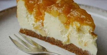 Weihnachtlicher Käsekuchen mit Spekulatiusboden und Bratapfel-Topping auf einem Teller